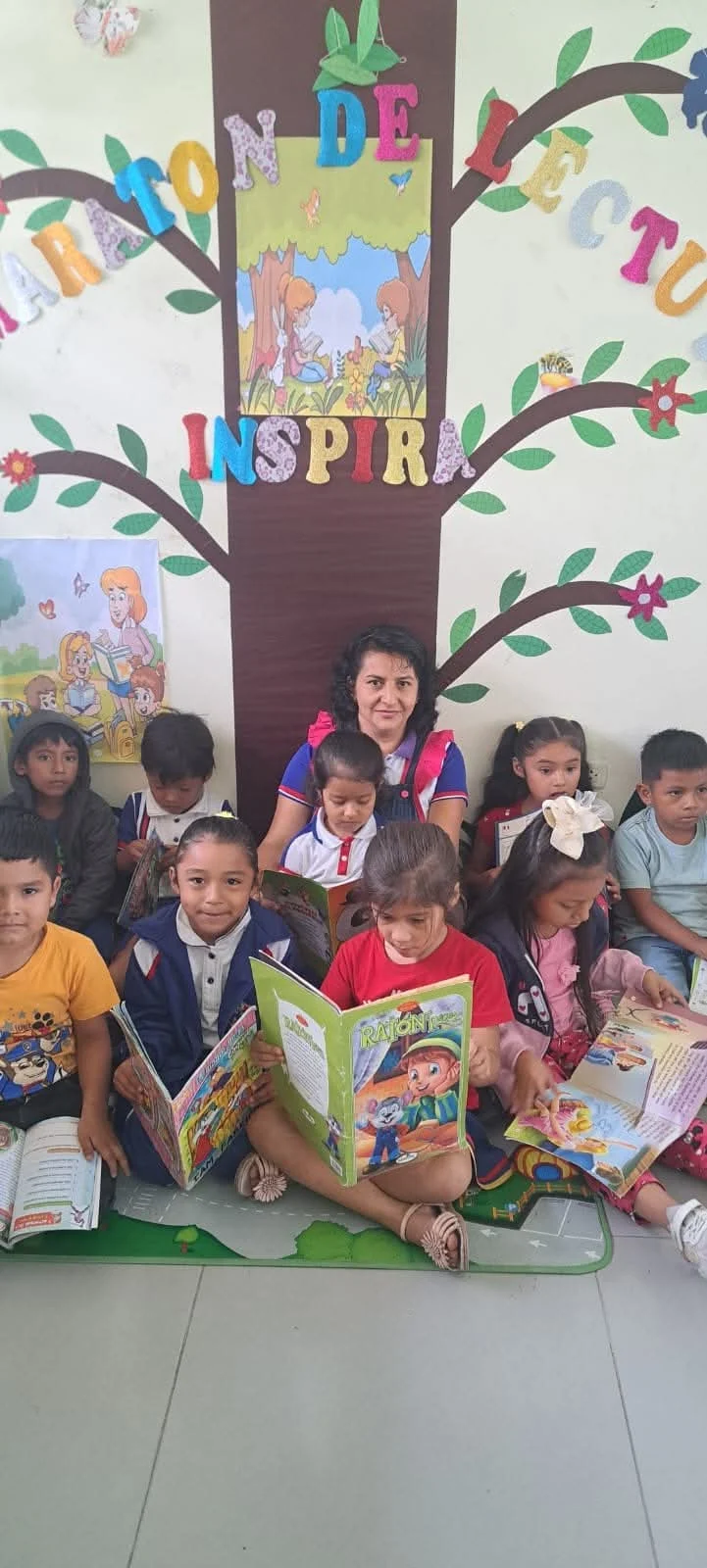Maestra y niños compartiendo libros en el espacio de lectura